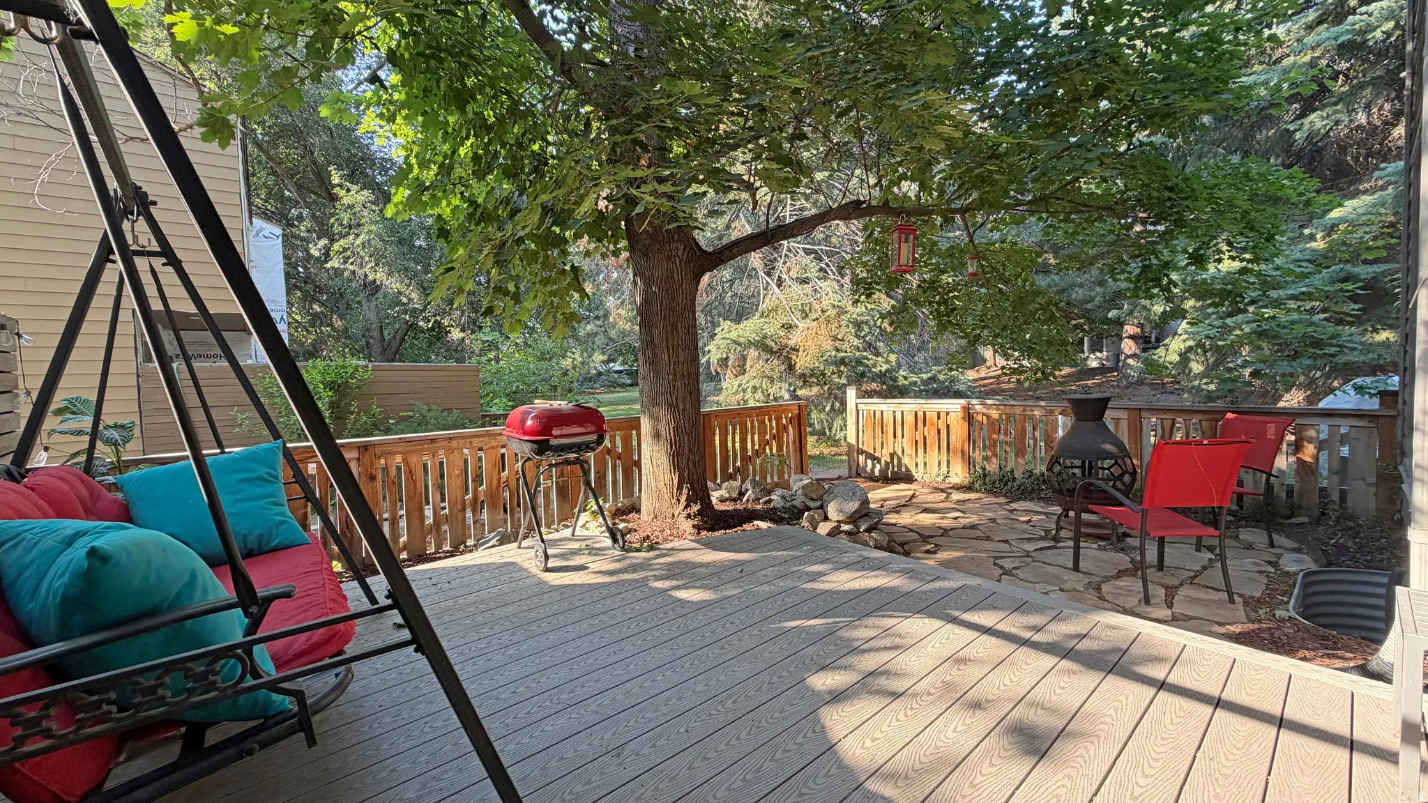 Expansive outdoor deck featuring wood-finish composite decking, a wooden railing, and mature trees providing natural shade