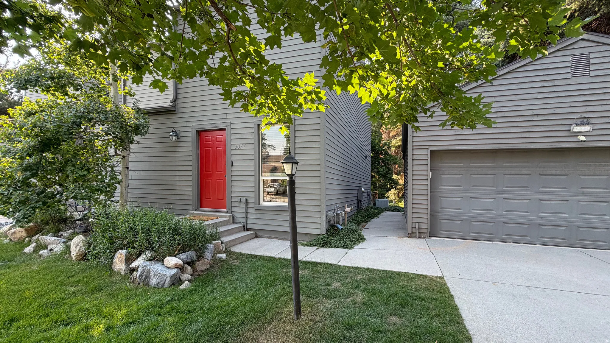 Gray horizontal siding exterior with a vibrant red entry door