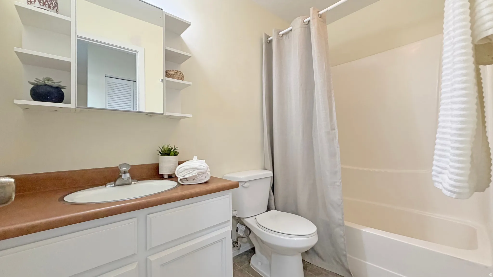 Bathroom featuring a white vanity with a laminate countertop, an integrated sink, and a chrome faucet