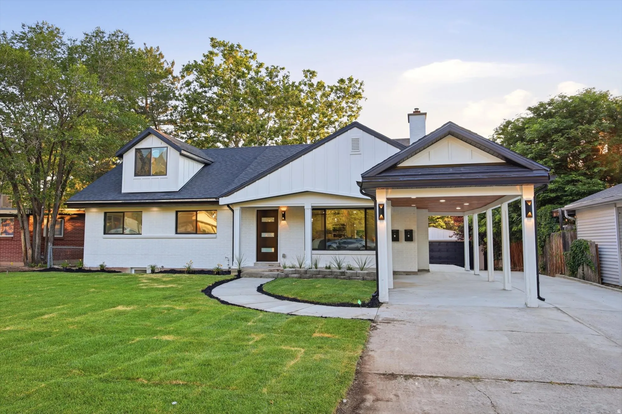 Modern white siding exterior with a dark roof and prominent carport