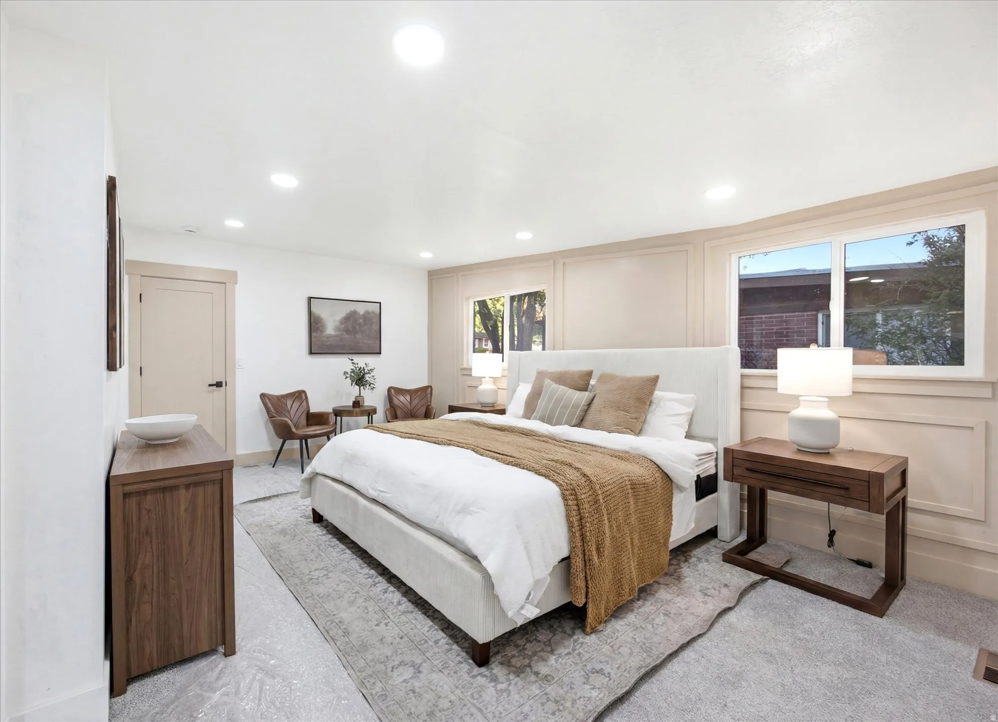 Spacious bedroom with light gray carpet flooring and recessed ceiling lighting