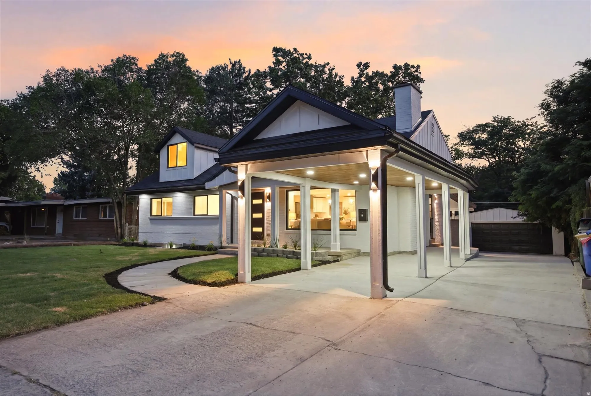Contemporary exterior featuring a carport, a concrete driveway, a curved pathway, and a manicured lawn