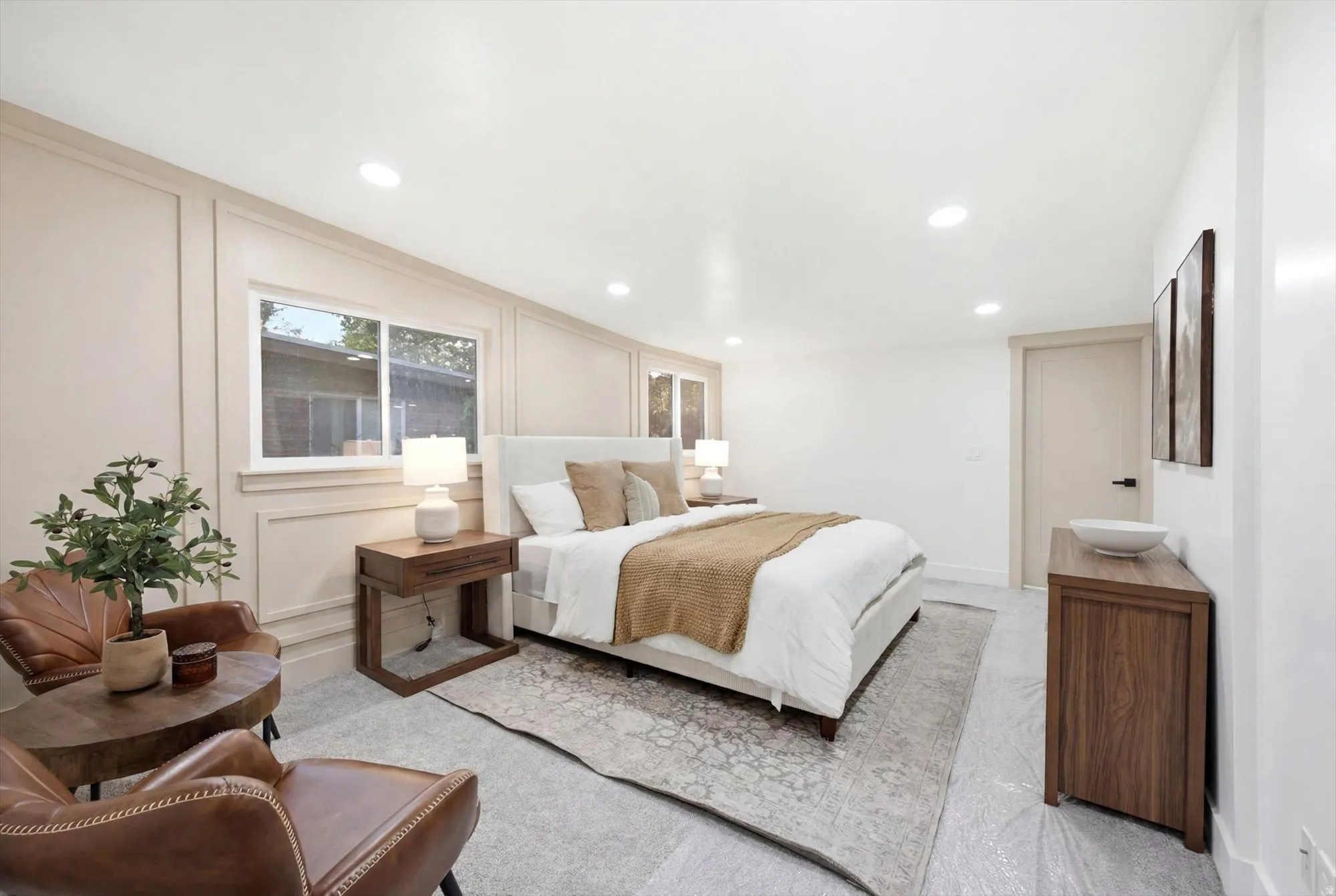 Spacious room featuring light-toned walls with decorative trim, recessed lighting, and a light-colored door