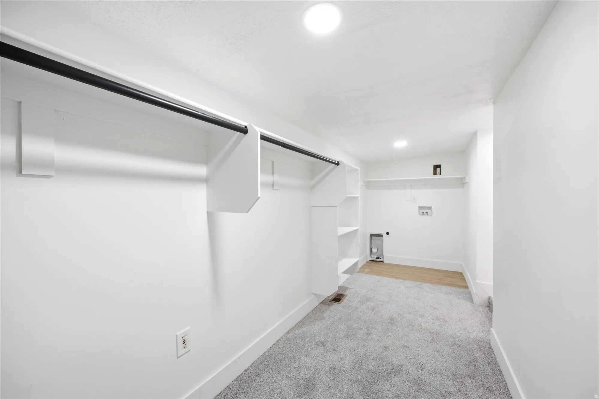 Dedicated laundry area with utility hookups and wood-finish flooring, complemented by built-in shelving