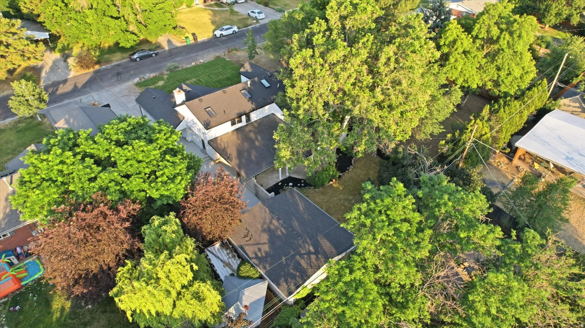 Residential property featuring a dark shingle roof and multiple mature trees