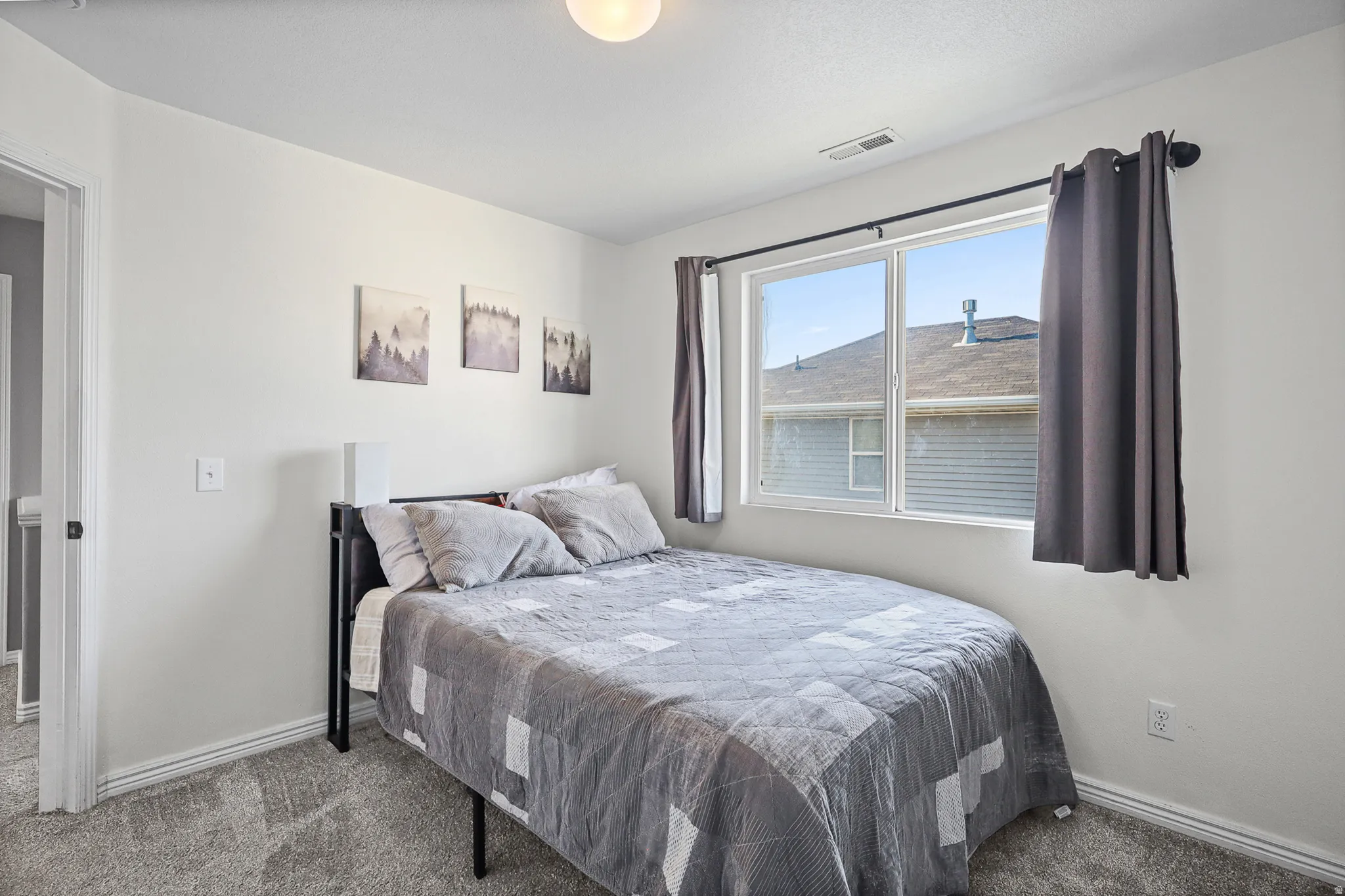 Bright bedroom featuring a large window, plush carpet, white baseboards, and a contemporary ceiling light fixture