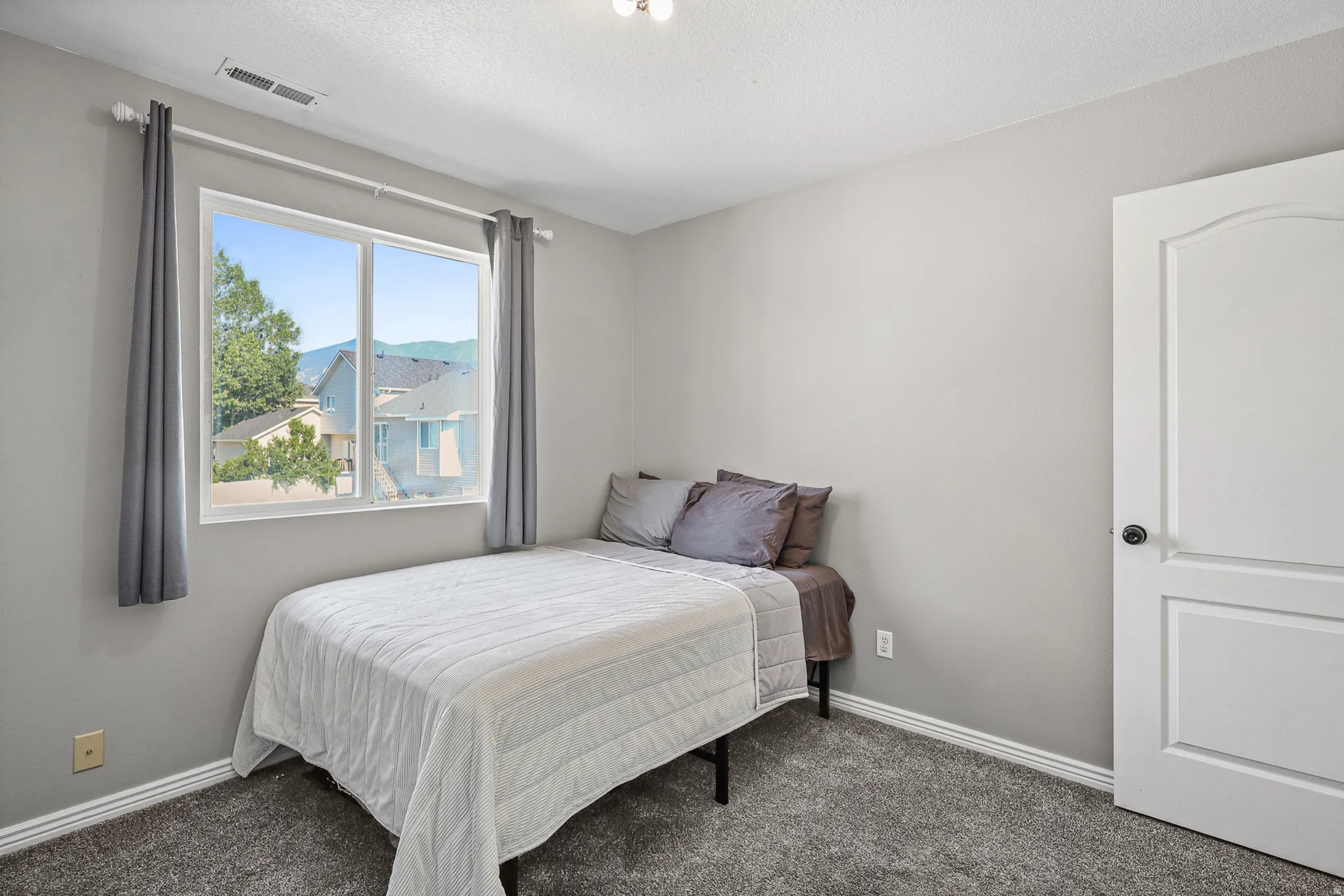 Carpeted room featuring a large window, neutral wall paint, white trim, and a white interior door with an arched panel design