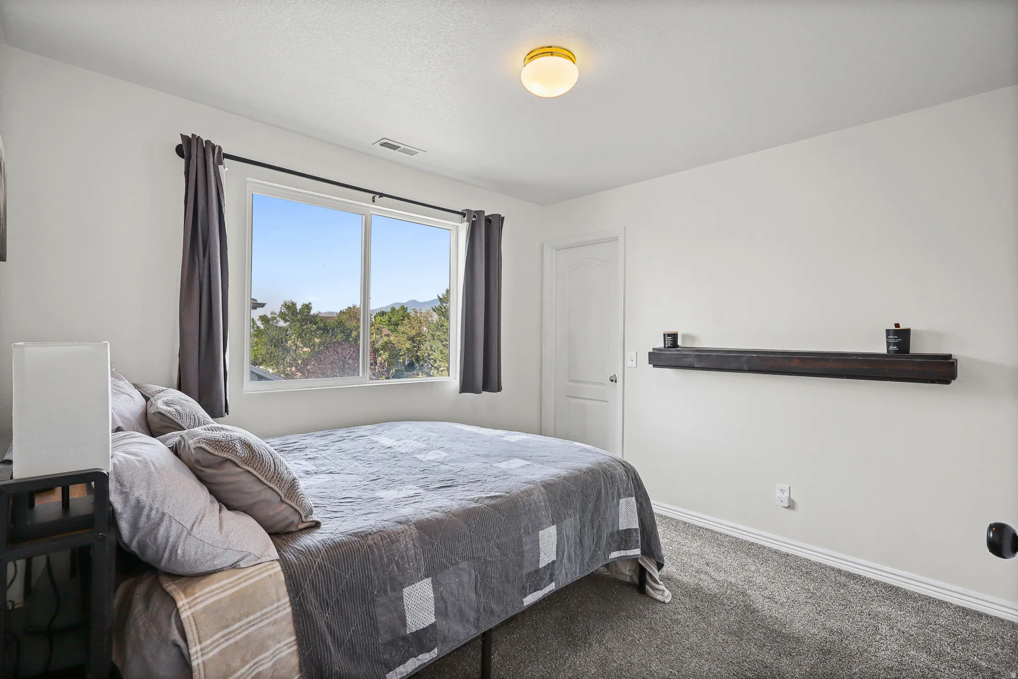 Bright interior space featuring a large window, neutral wall paint, and plush carpeting