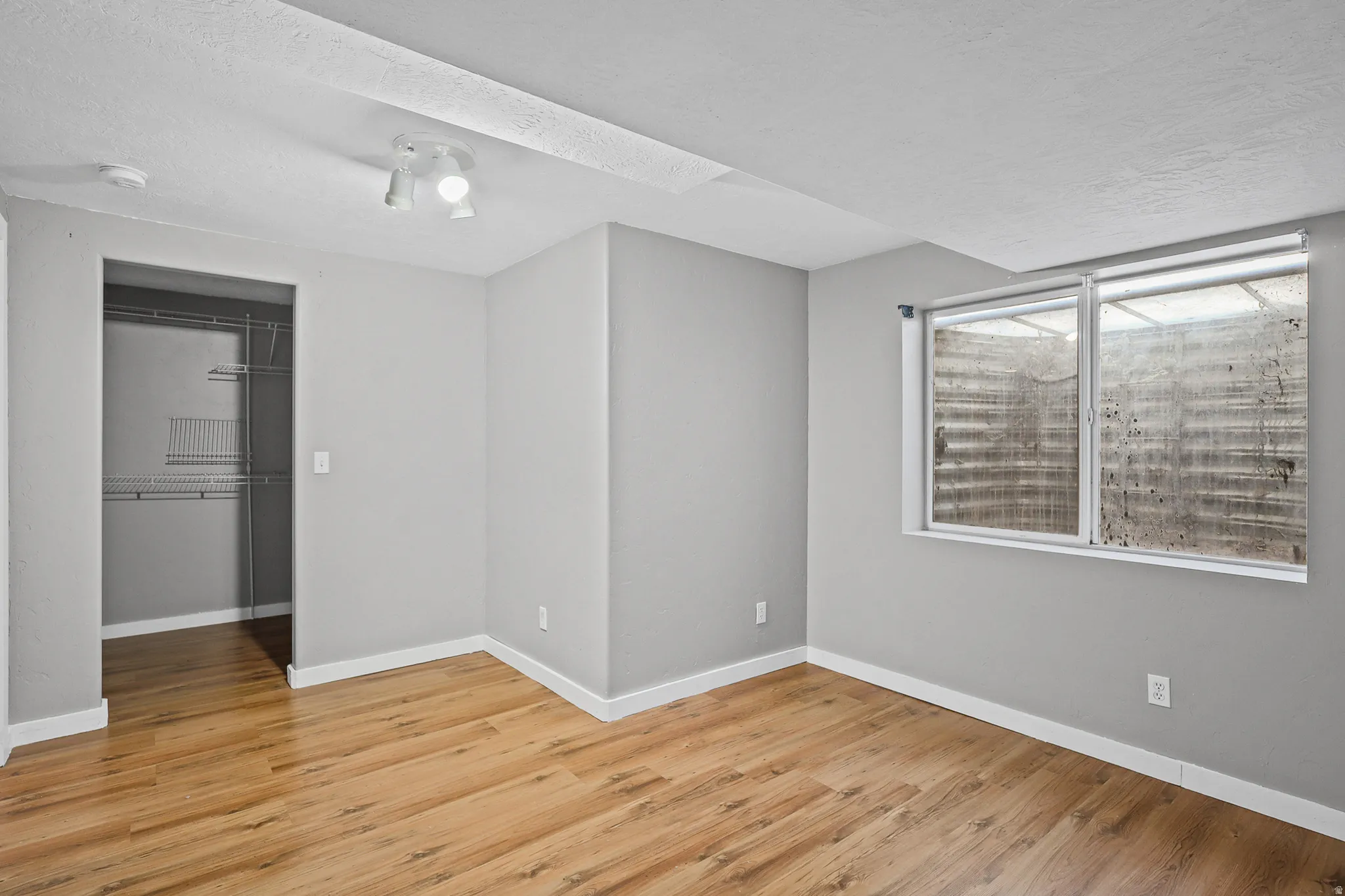 Room featuring wood-finish flooring, light gray wall paint, and white baseboards