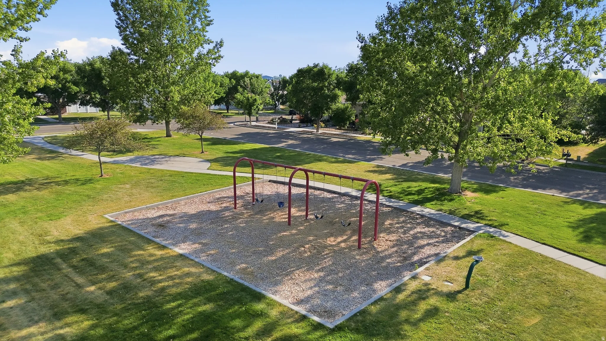 Outdoor play area with a swing set, wood chip surfacing, and surrounding green lawn