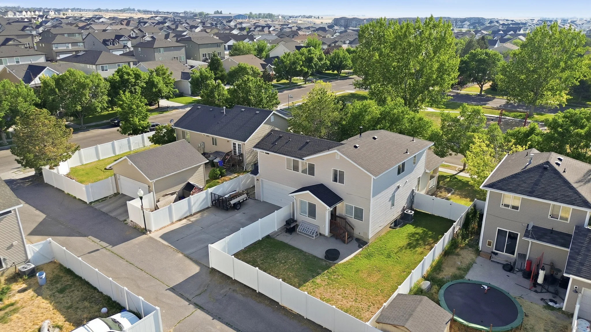 Two-story residence featuring a front entry porch, a fenced rear yard with green space, and a detached garage with an extended driveway