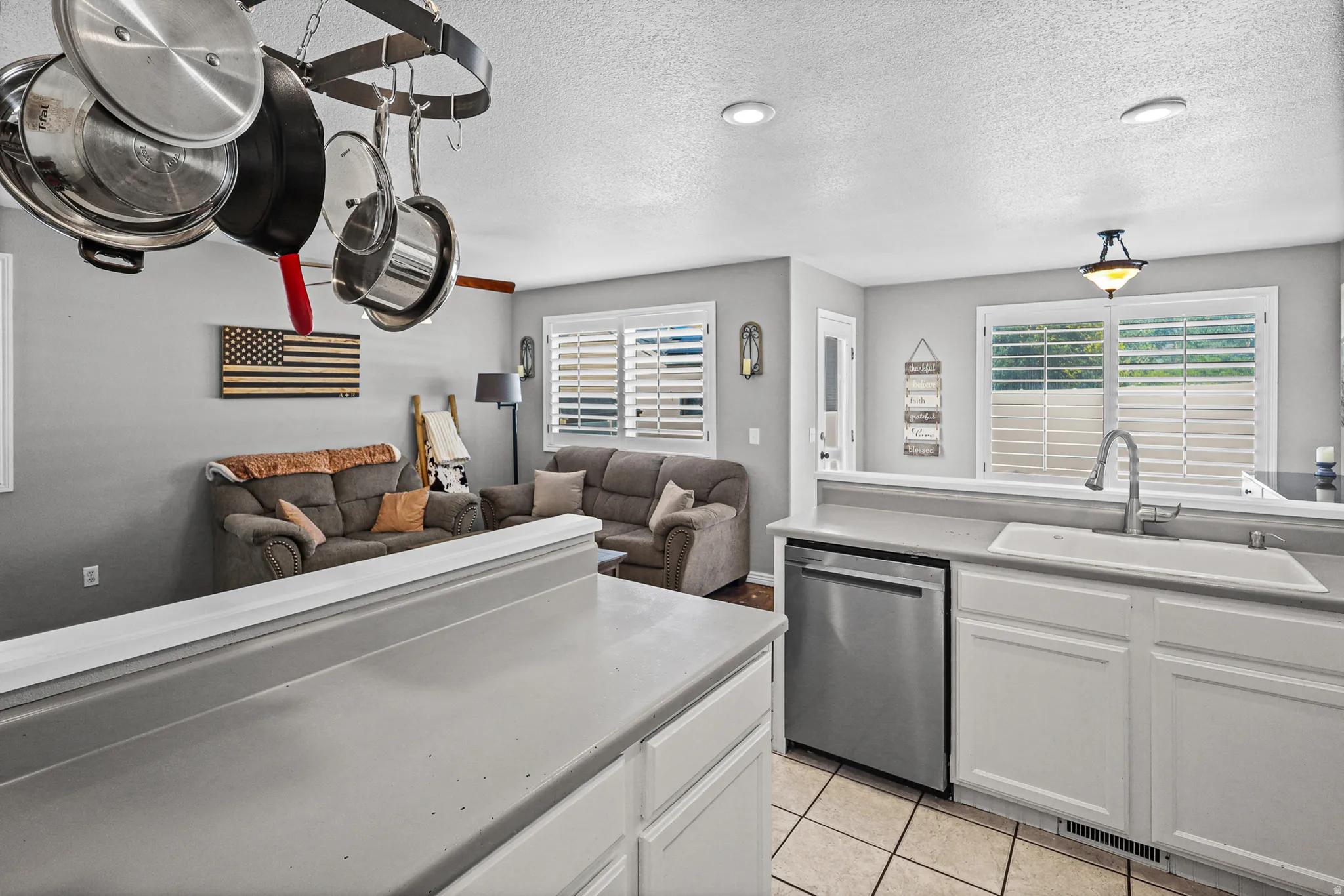 Kitchen space with white cabinetry, stainless steel dishwasher, and a white single-basin sink featuring a gooseneck faucet