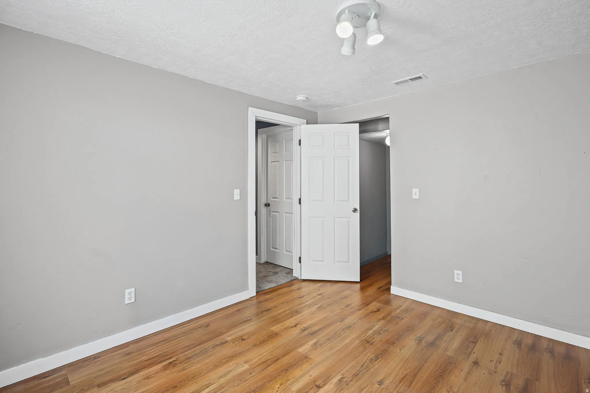 Room featuring wood-finish flooring, light gray wall paint, and white trim