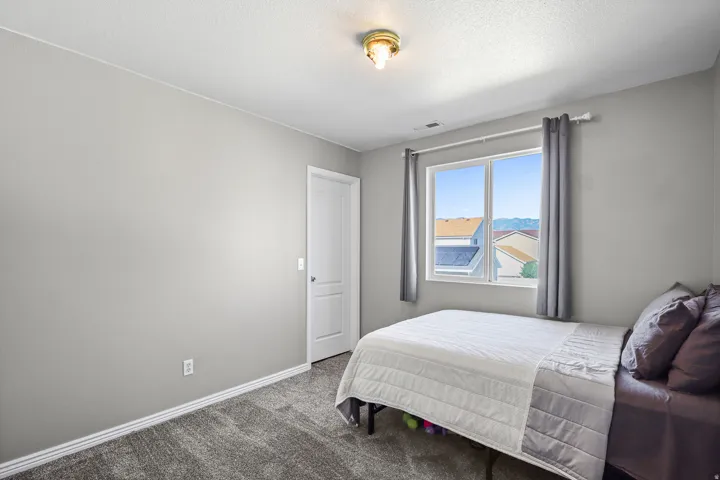 Carpeted interior space featuring light grey walls, a white paneled door, a window with grey curtains, and white trim