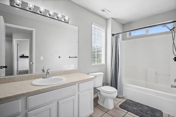 Bathroom featuring a single vanity with a laminate countertop, white cabinetry, and a full-width mirror