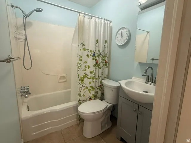 Full bathroom featuring a tub/shower combination with a single-handle faucet, a toilet, a vanity with a white basin and chrome faucet, and a wall-mounted mirror