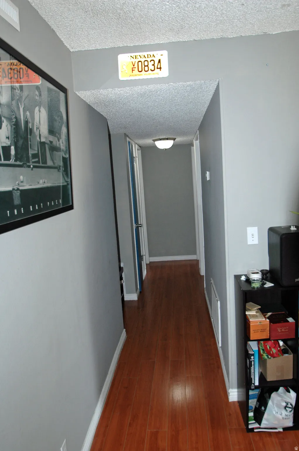 Hallway with wood-finish flooring, light gray wall paint, and white baseboards