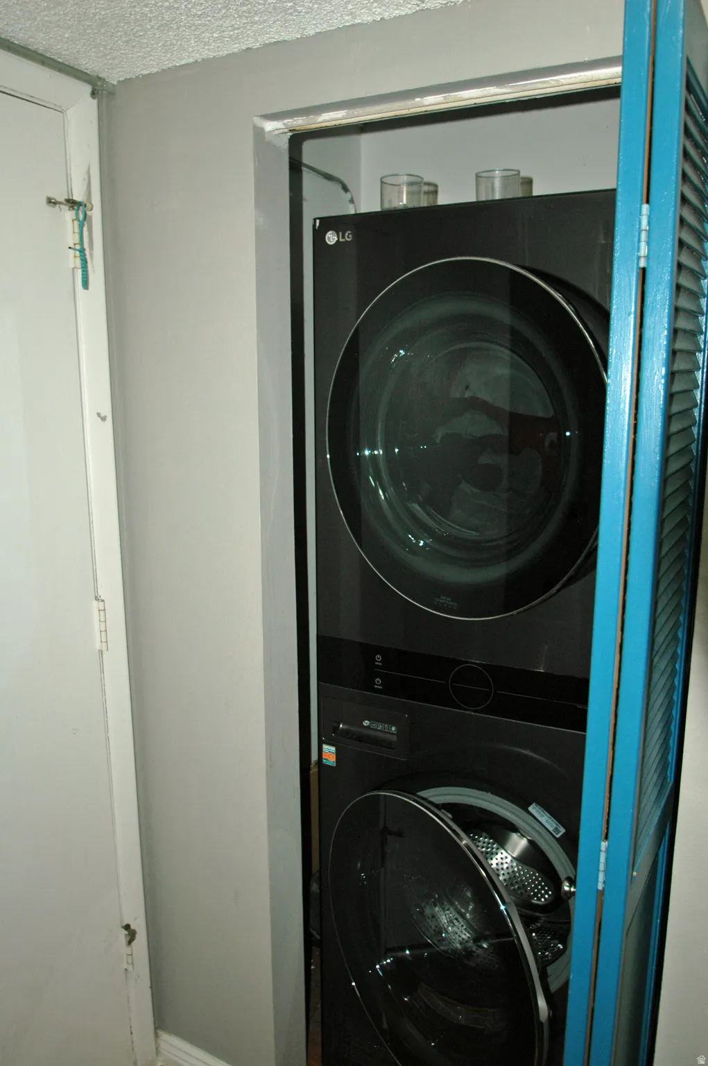 Integrated laundry closet featuring a stacked washer and dryer unit