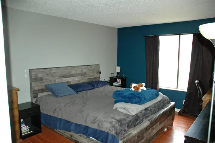 Spacious primary bedroom a large window with privacy coverings and half bath.