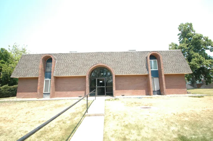 Brick exterior building featuring a prominent arched entry with glass doors