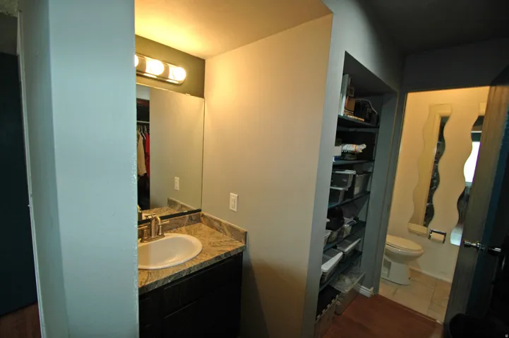 Vanity area featuring a built-in cabinet with brushed nickel hardware, an undermount sink, and a granite countertop
