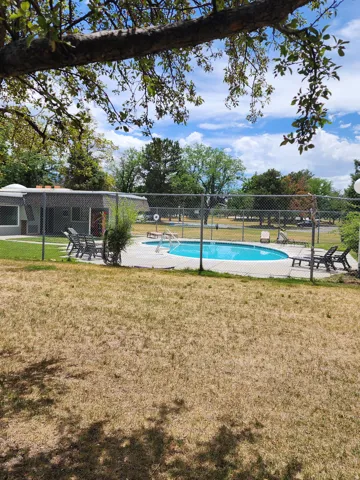 Fenced in-ground swimming pool with surrounding patio decking