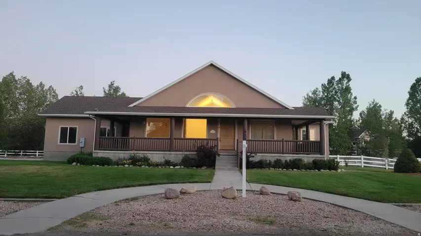 Stucco exterior residence featuring a covered front porch with dark wood railings and columns