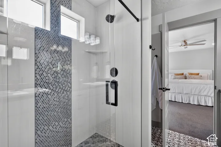 Glass-enclosed shower with a black matte hardware and a mosaic tile accent wall