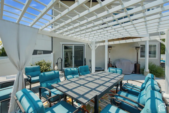 Spacious outdoor patio featuring a white pergola, sliding glass door access, and a durable composite deck surface