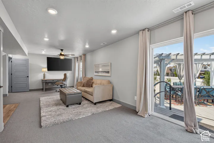 Recessed ceiling lighting, ceiling fan, carpeted flooring, sliding glass door, and an exterior pergola