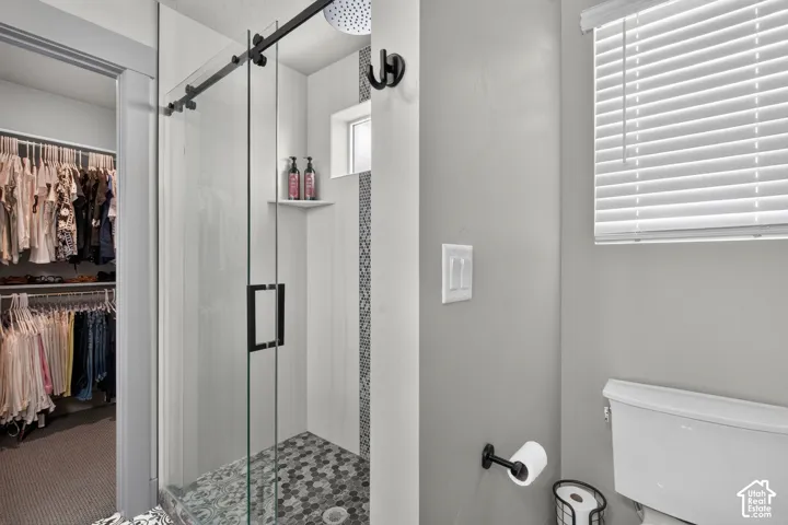 Walk-in shower with a frameless glass door, dark-toned hardware, hexagon-patterned floor tiles, and a built-in shower niche