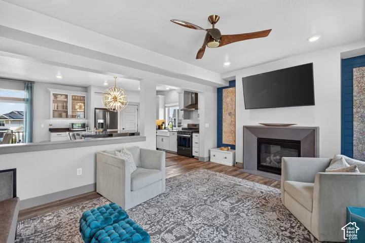 Integrated living space featuring LVP flooring, a contemporary fireplace with a stone surround, and an adjacent kitchen with stainless steel appliances