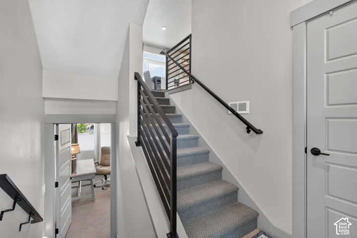 Carpeted staircase with modern metal railing and black handrail