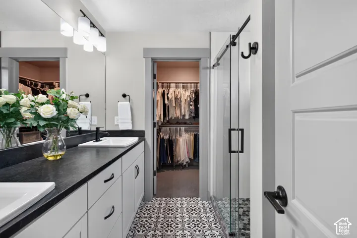 Dual vanity with white cabinetry and dark countertops, individual white rectangular sinks, and a large wall mirror