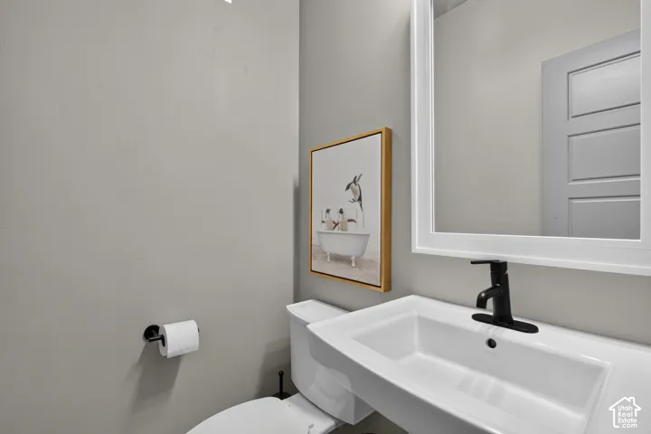 White framed mirror positioned above a white sink with a matte black faucet