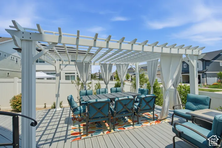 Expansive deck featuring a white pergola with privacy drapes, composite decking, and a surrounding privacy fence