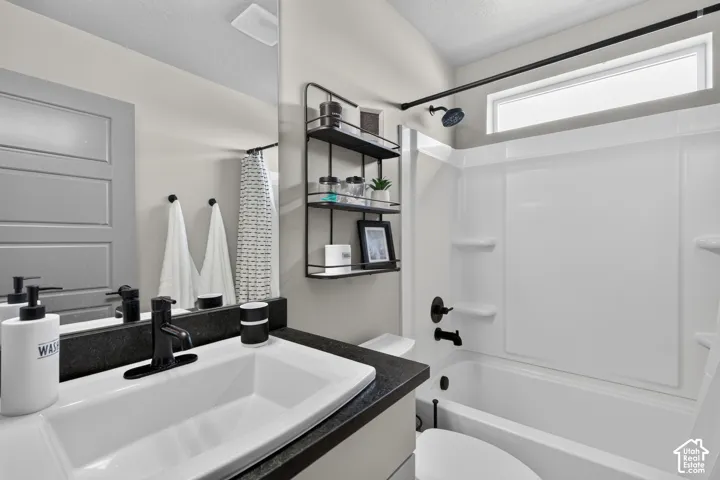 Bathroom featuring a white integrated sink, dark countertop, and matte black fixtures
