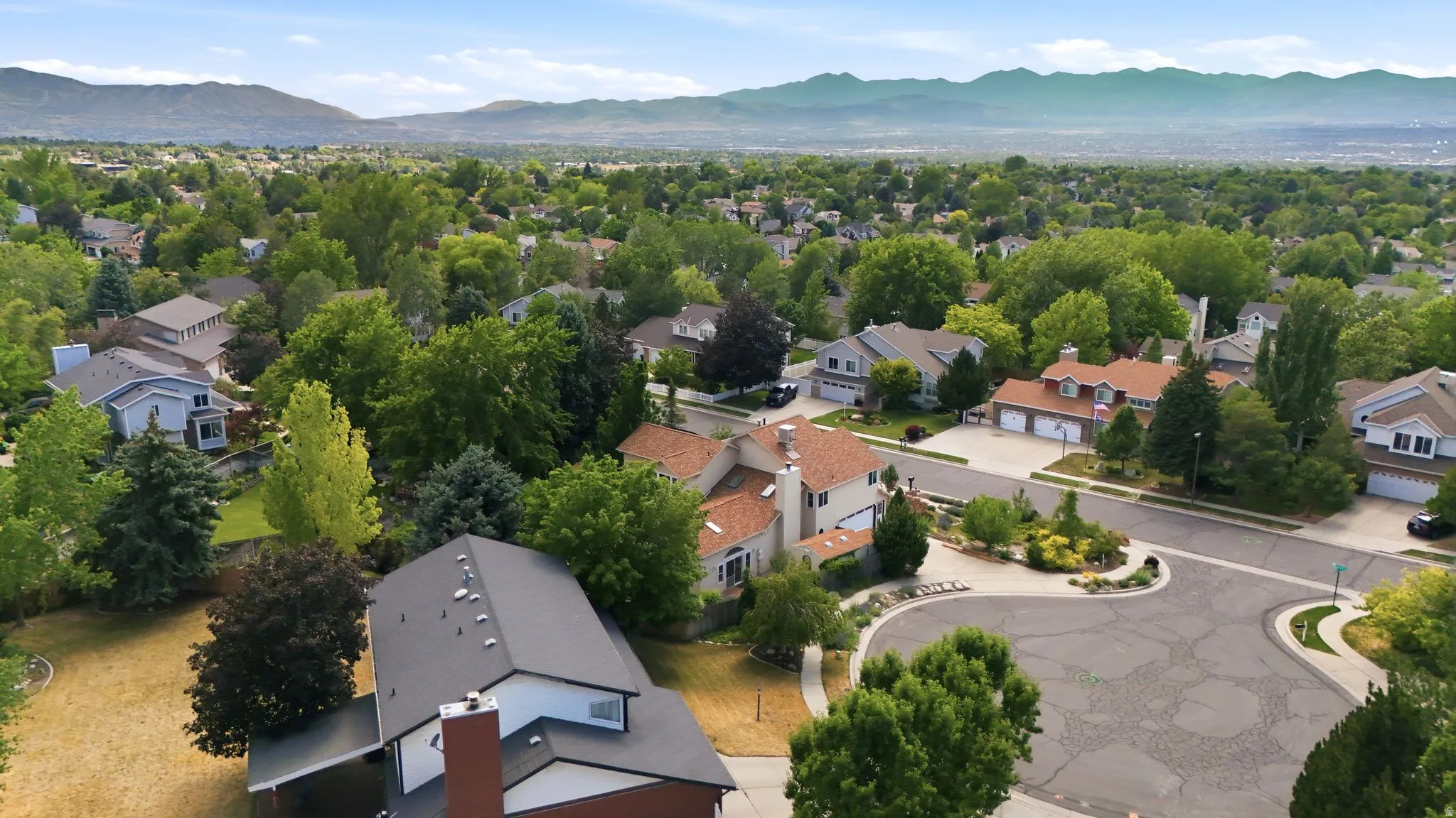 Residential neighborhood featuring mature trees, cul-de-sac street patterns, and mountain backdrops