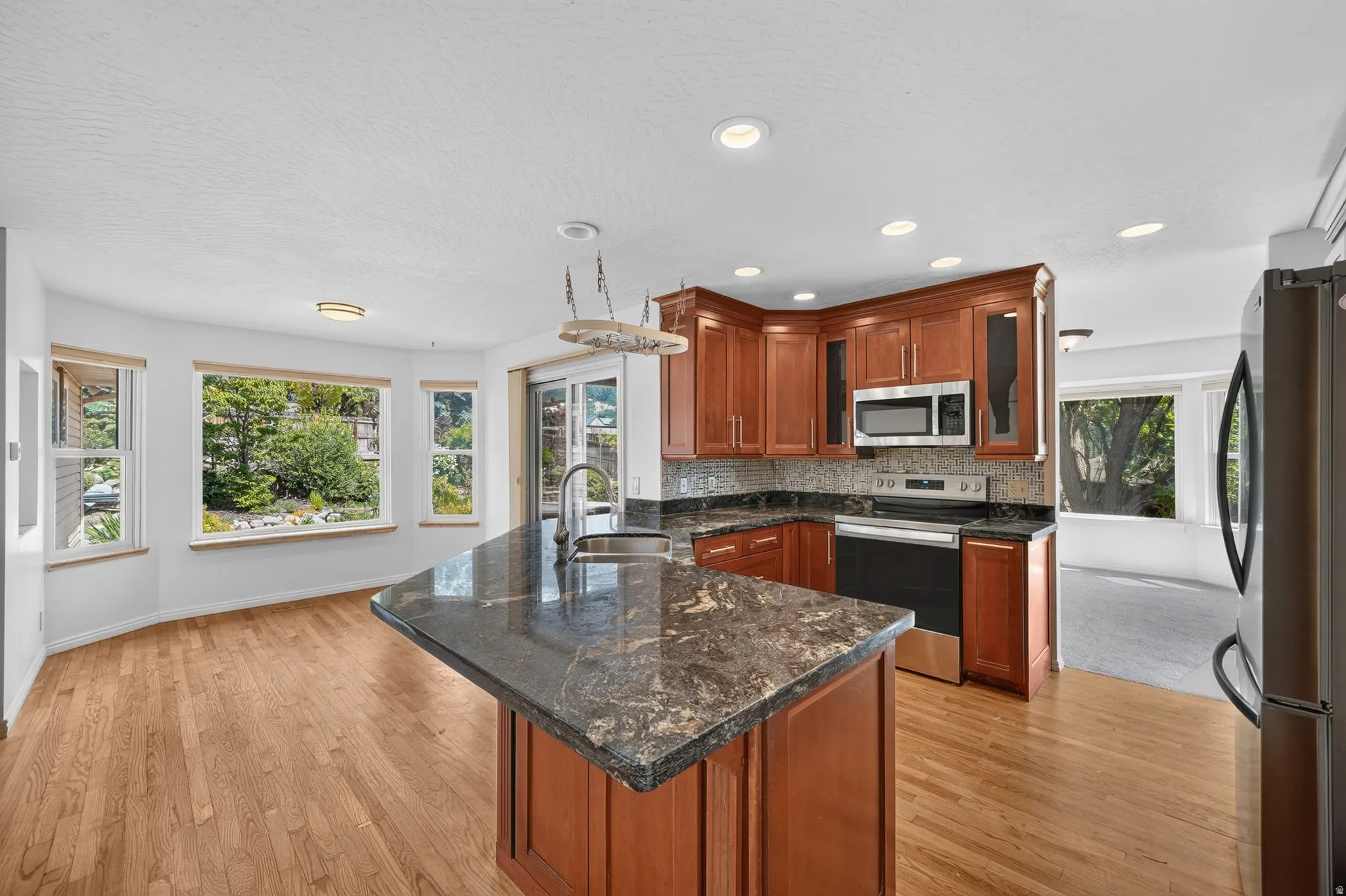 Kitchen with a central island featuring a sink and a dark stone countertop