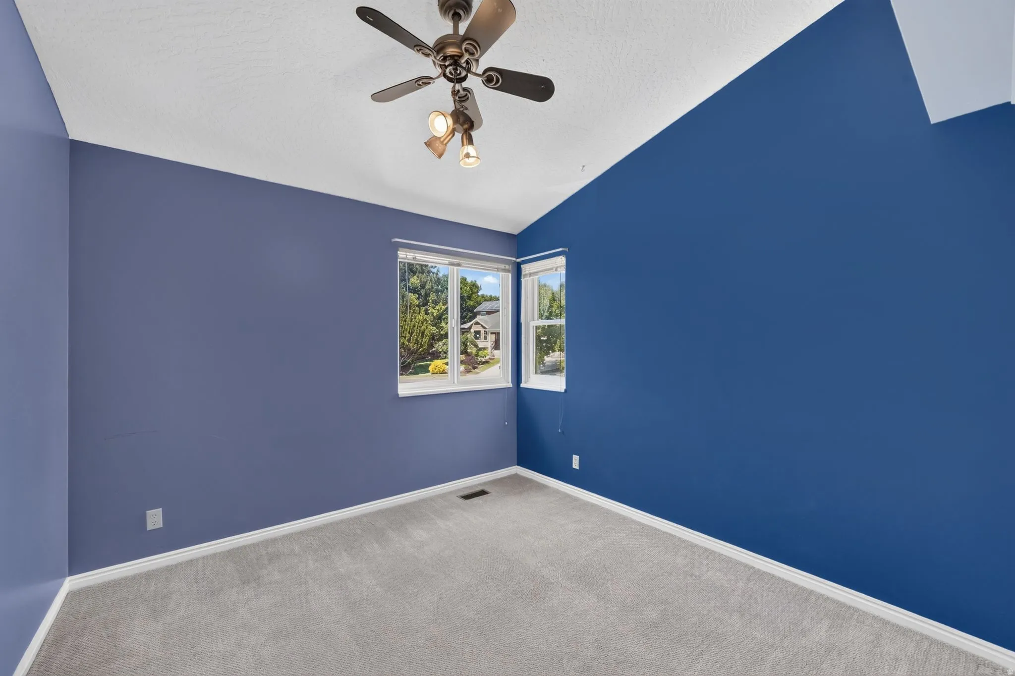 Room featuring vaulted ceilings, a ceiling fan with integrated lighting, and light gray carpeting
