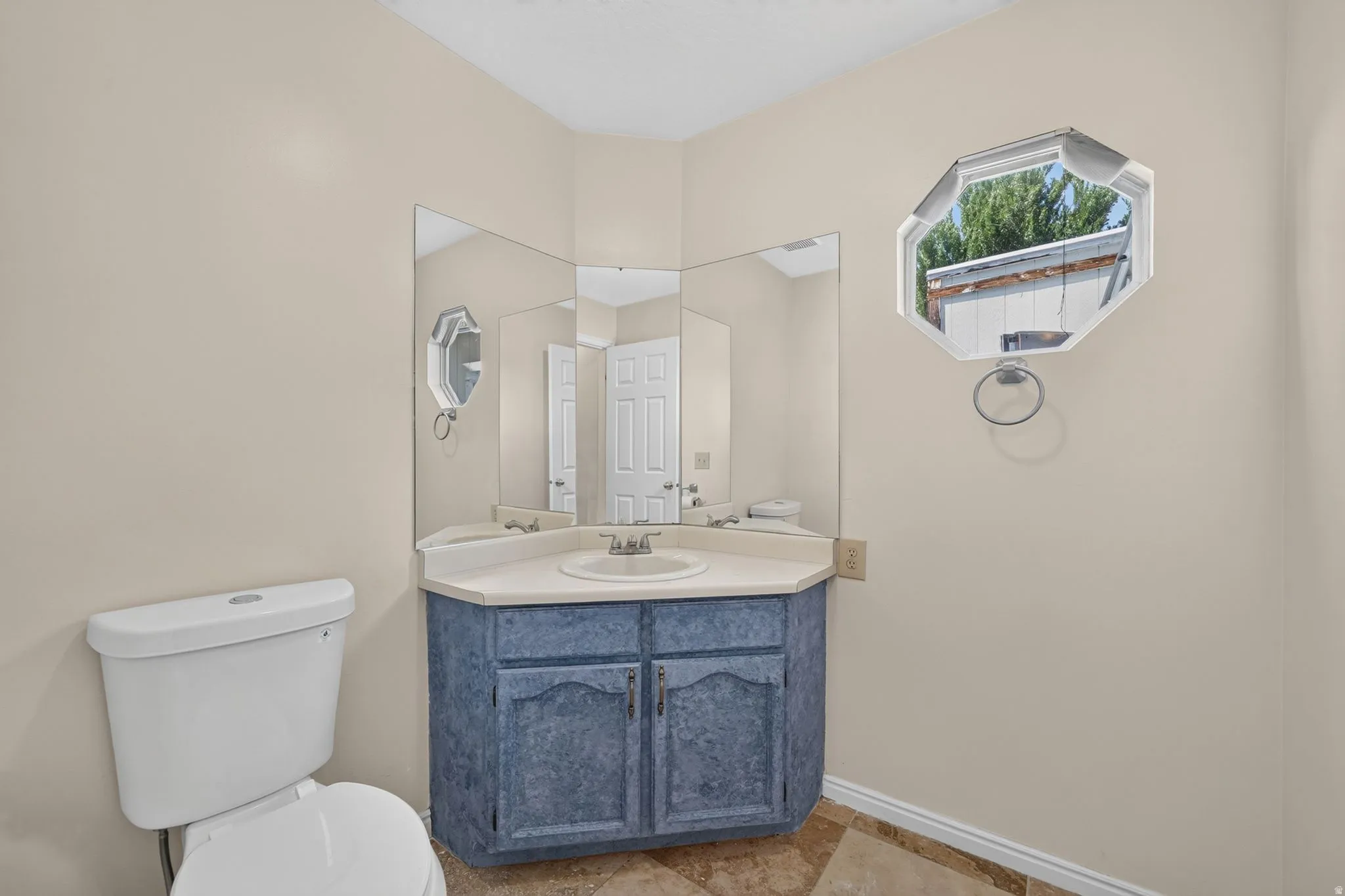 Bathroom featuring a corner vanity with a single sink, an octagonal window, and a wall-mounted mirror