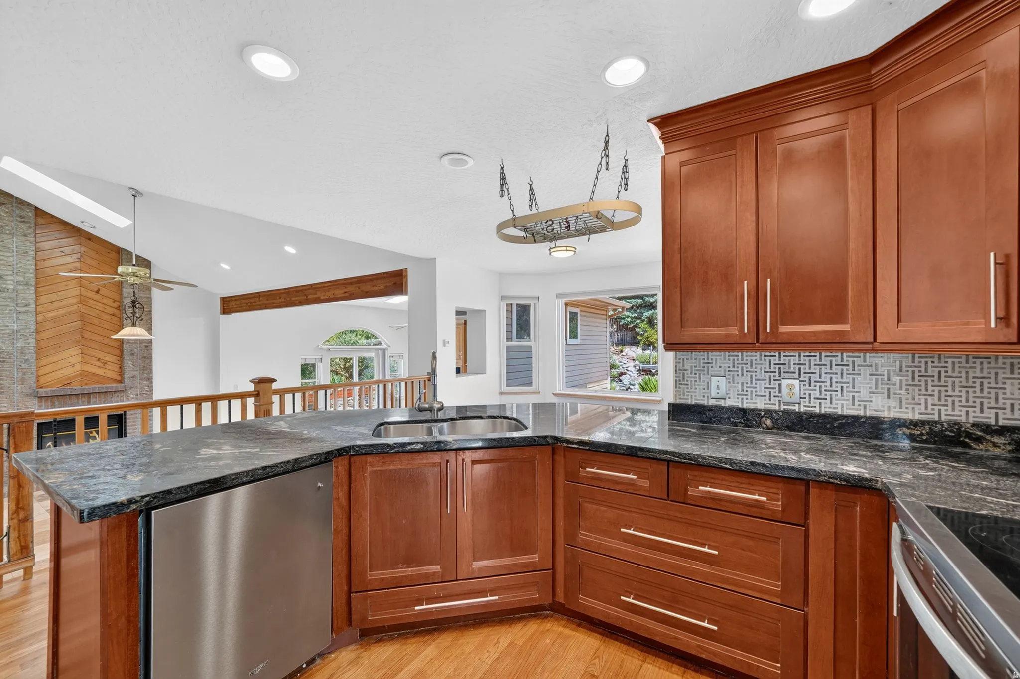 Kitchen featuring wood cabinetry, stainless steel appliances, dark stone countertops, and a mosaic tile backsplash