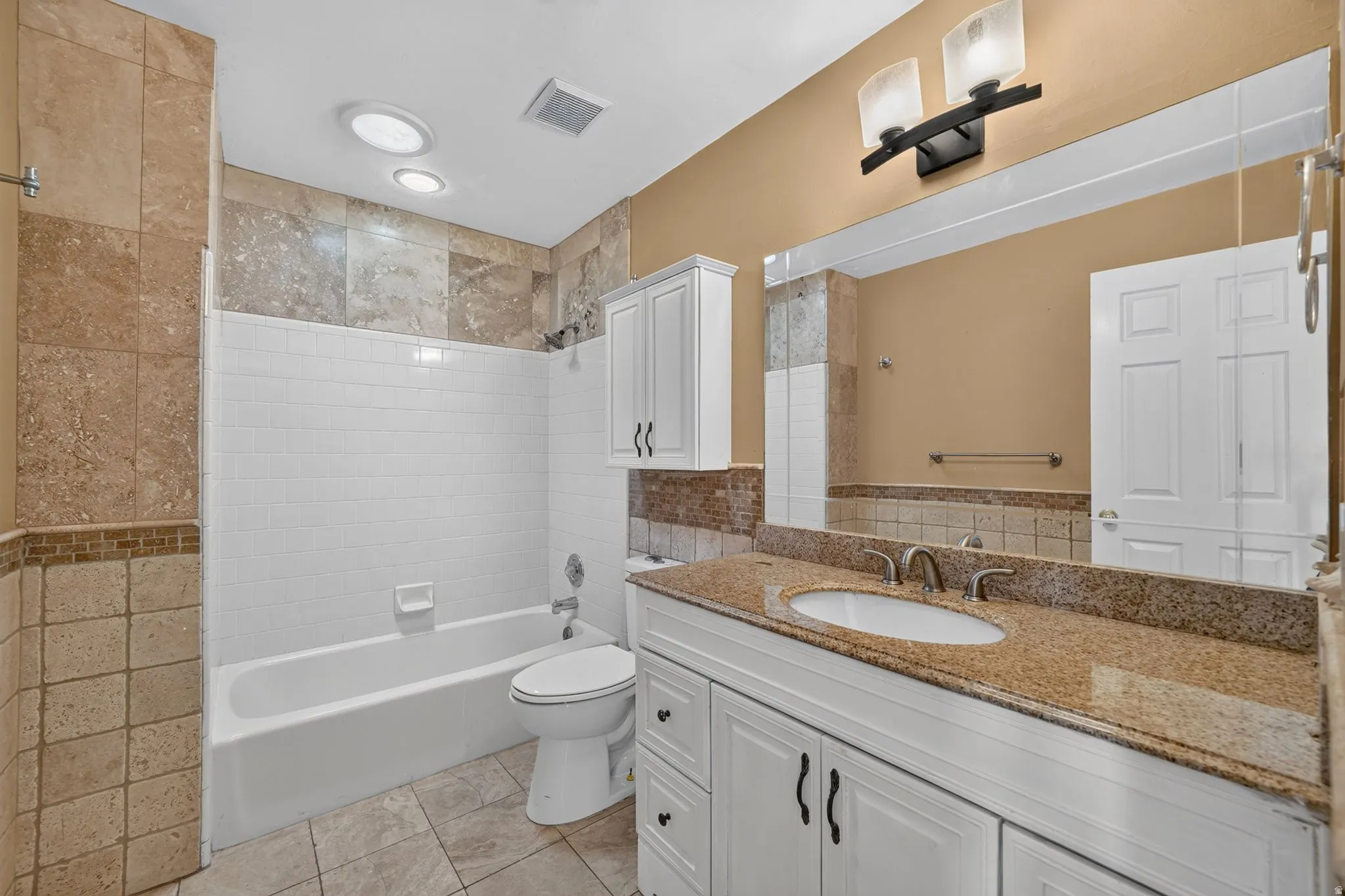 Bathroom featuring a white vanity with a granite countertop, undermount sink, and brushed nickel faucet