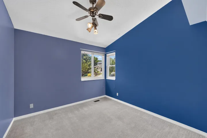 Room featuring vaulted ceilings, a ceiling fan with integrated lighting, and light gray carpeting