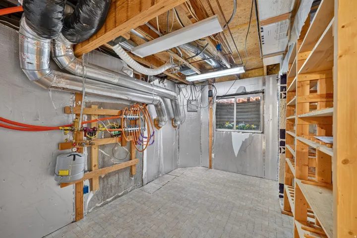 Utility room featuring exposed ceiling joists, ductwork, and built-in wooden shelving