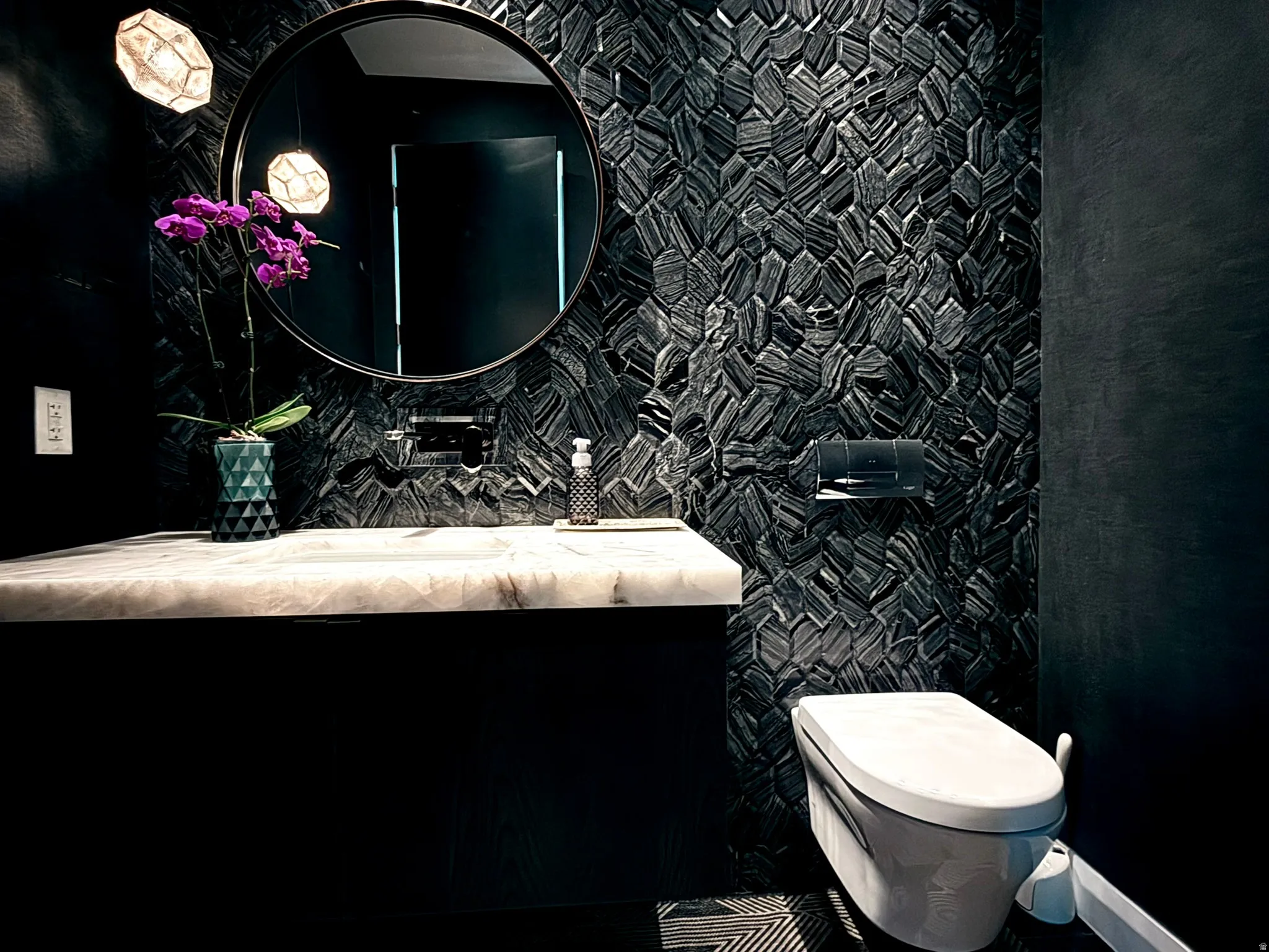 Floating vanity with a light-toned stone countertop, round mirror, and wall-mounted faucet