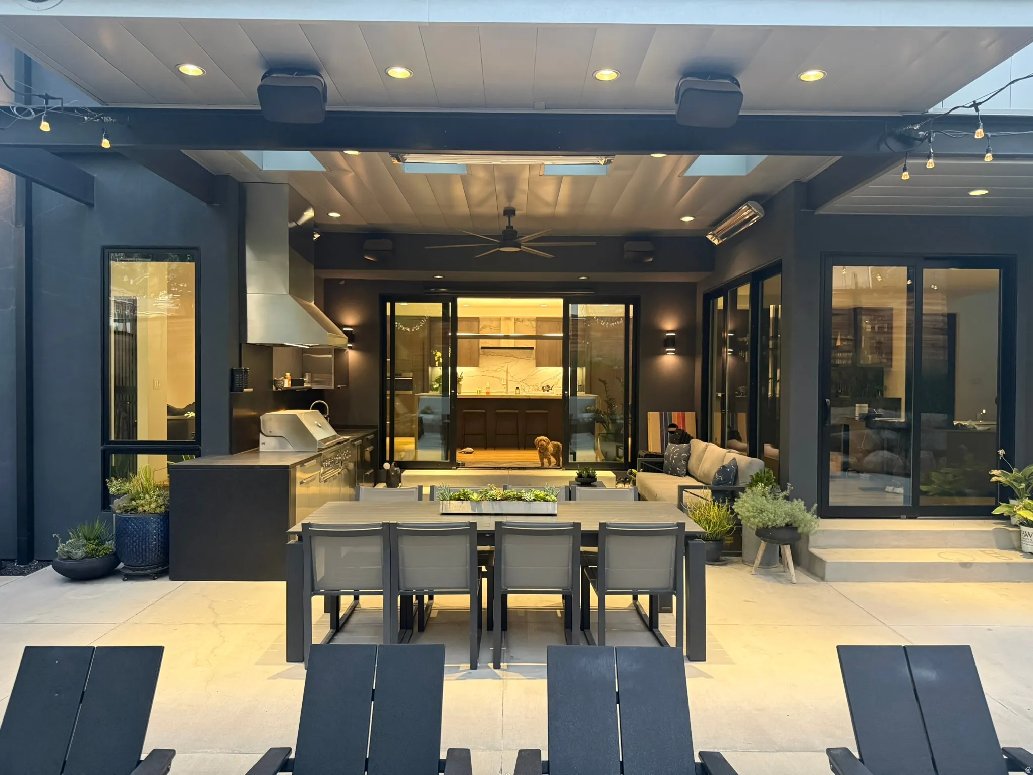 Expansive covered patio featuring an outdoor kitchen with stainless steel appliances, a built-in outdoor grill, and a commercial-grade range hood