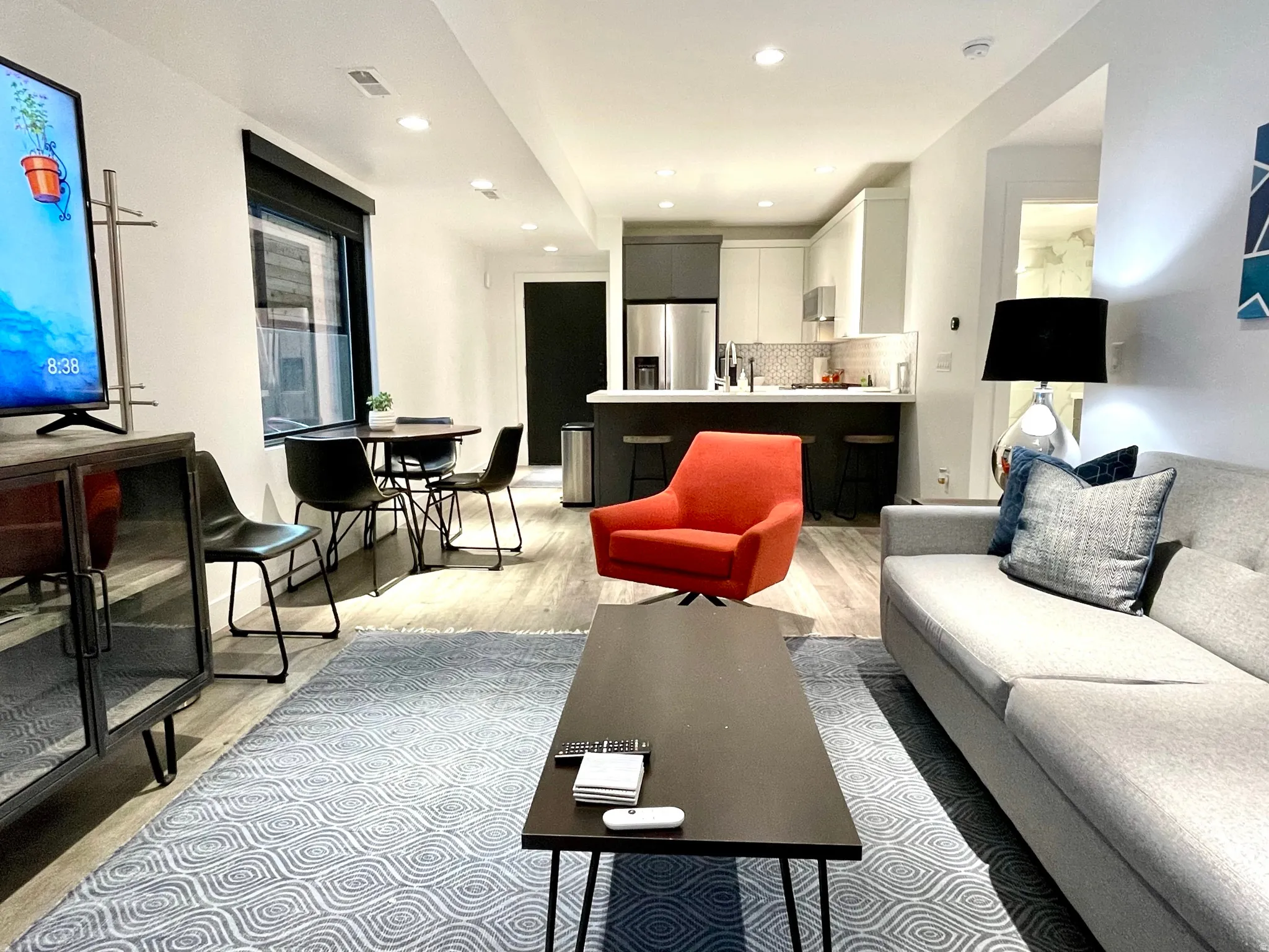 Open-concept living area featuring wood-finish flooring, recessed lighting, and a window with roller shades