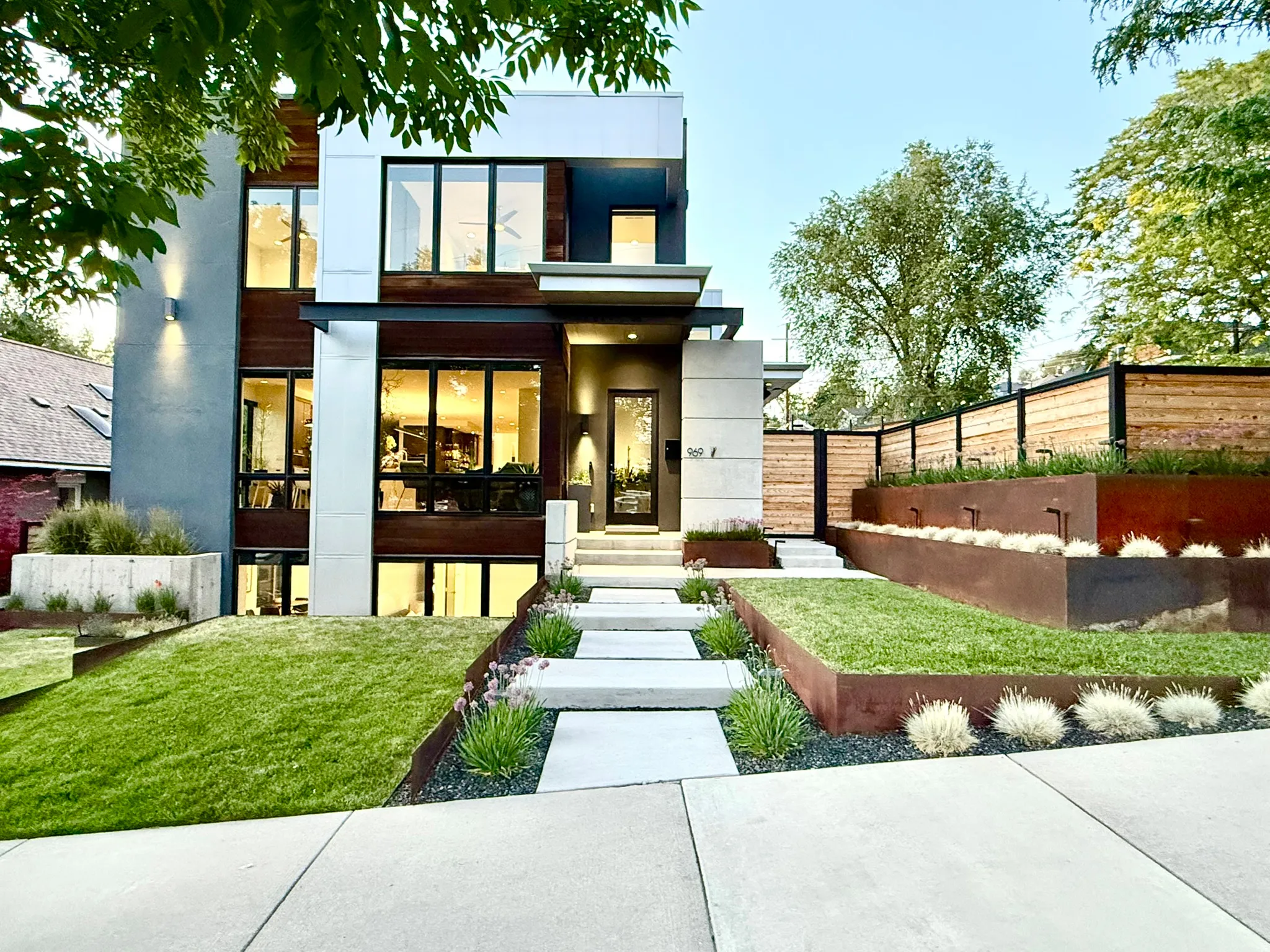 Modern architectural residence featuring multi-level landscaping with integrated lighting