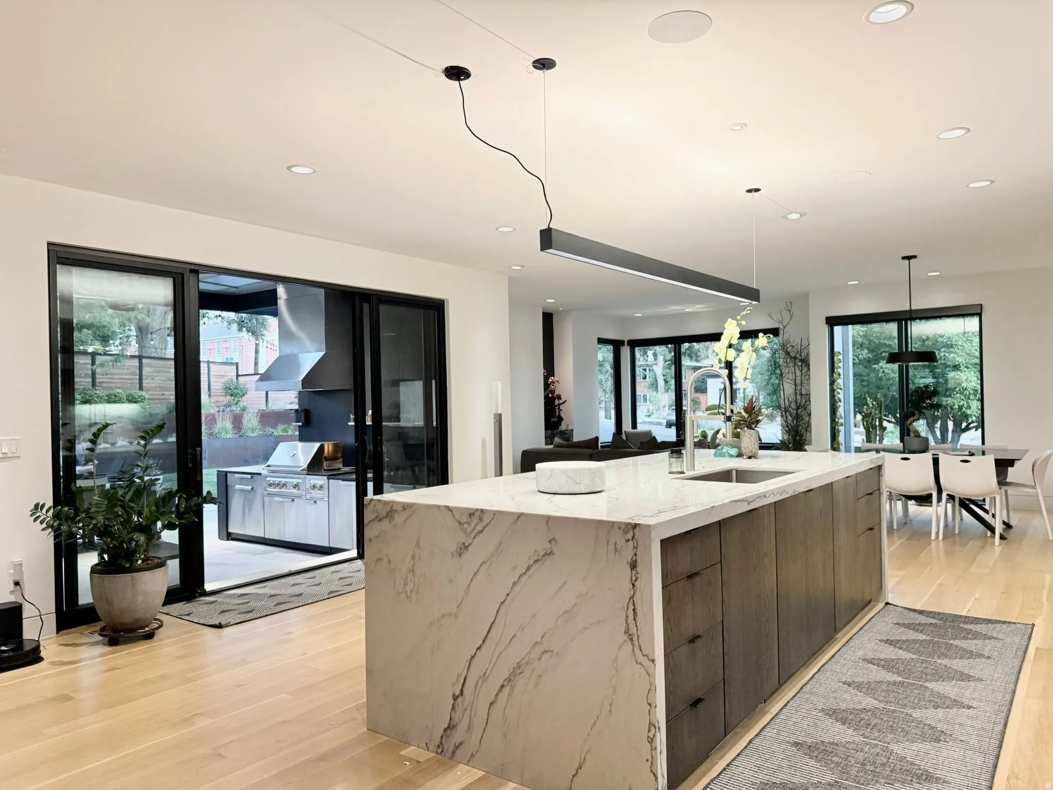 Kitchen island featuring a waterfall edge countertop, integrated sink, and modern pendant lighting